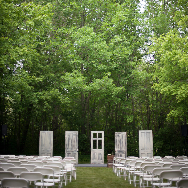 4 distressed doors act as the back drop to this outdoor wedding in the Meadows along with chairs
