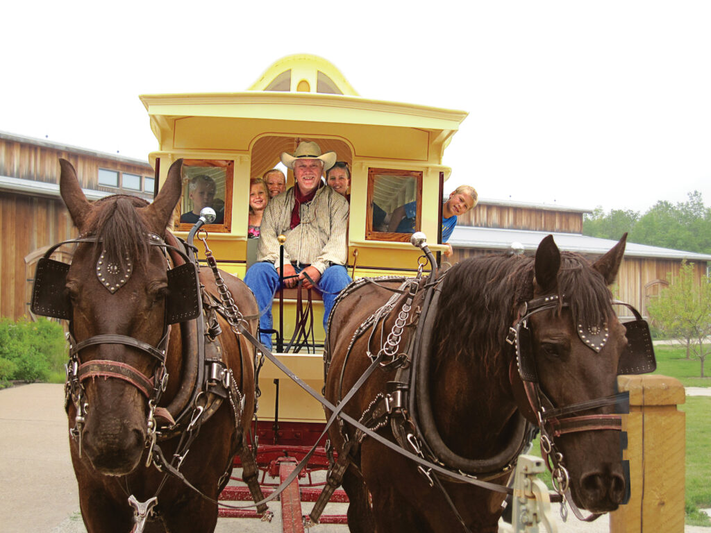 A man with a wagon full of guests drives the horses with a smile on his face during his employment