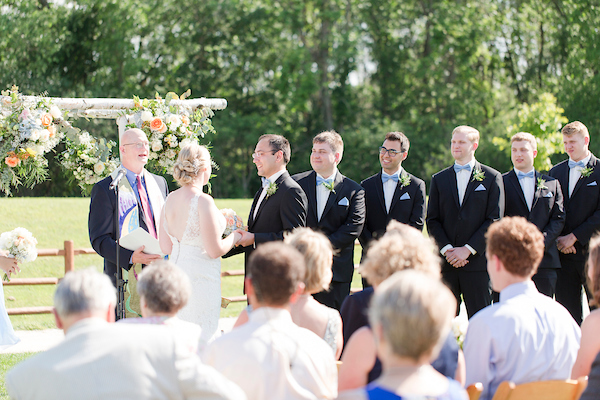 A wedding ceremony on the lawn, featuring the officiant, the bride, groom, and the groomsmen.