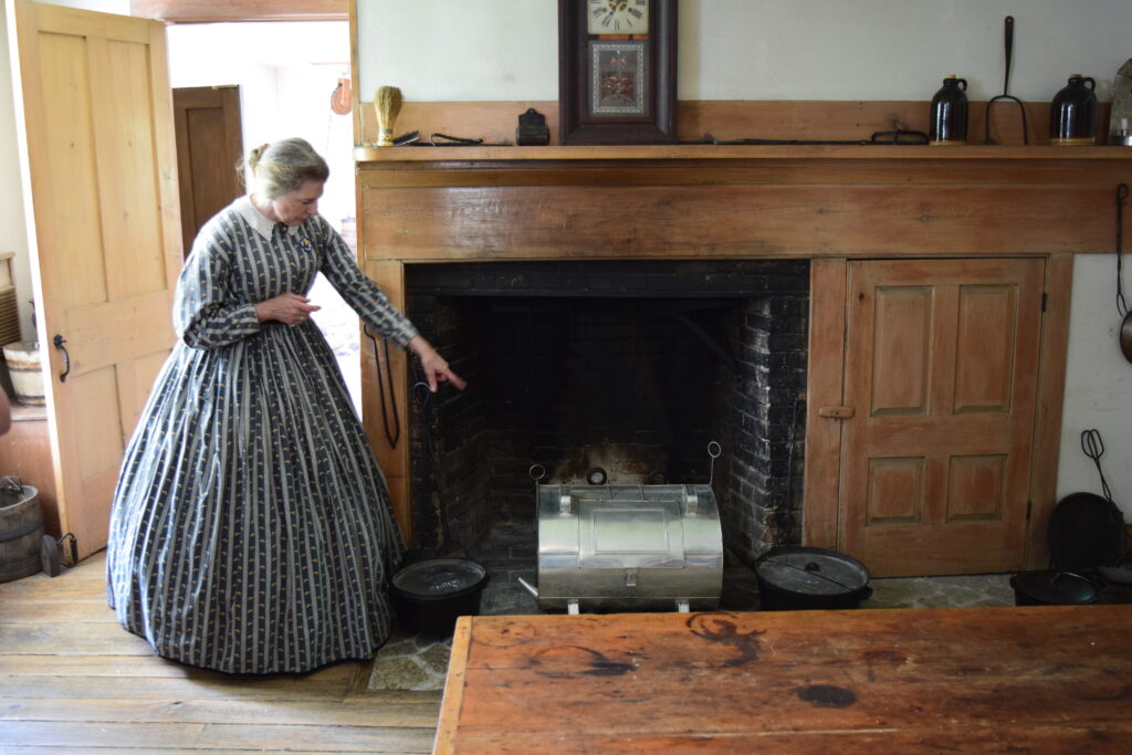 A women in period clothes shows people a fireplace during her employment